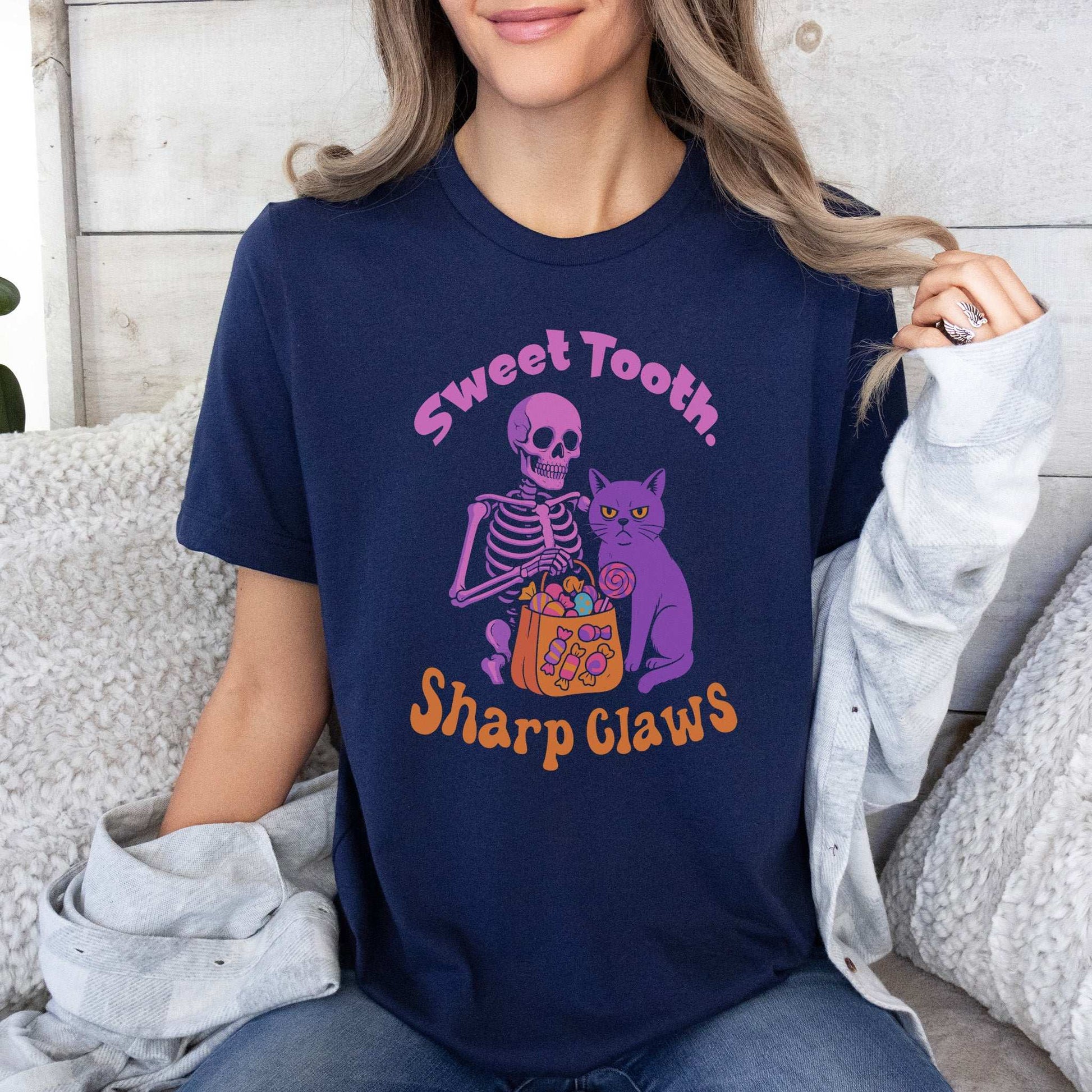 Skeleton and Grumpy Cat Halloween T-shirt with text 'Sweet Tooth, Sharp Claws' on a navy background.