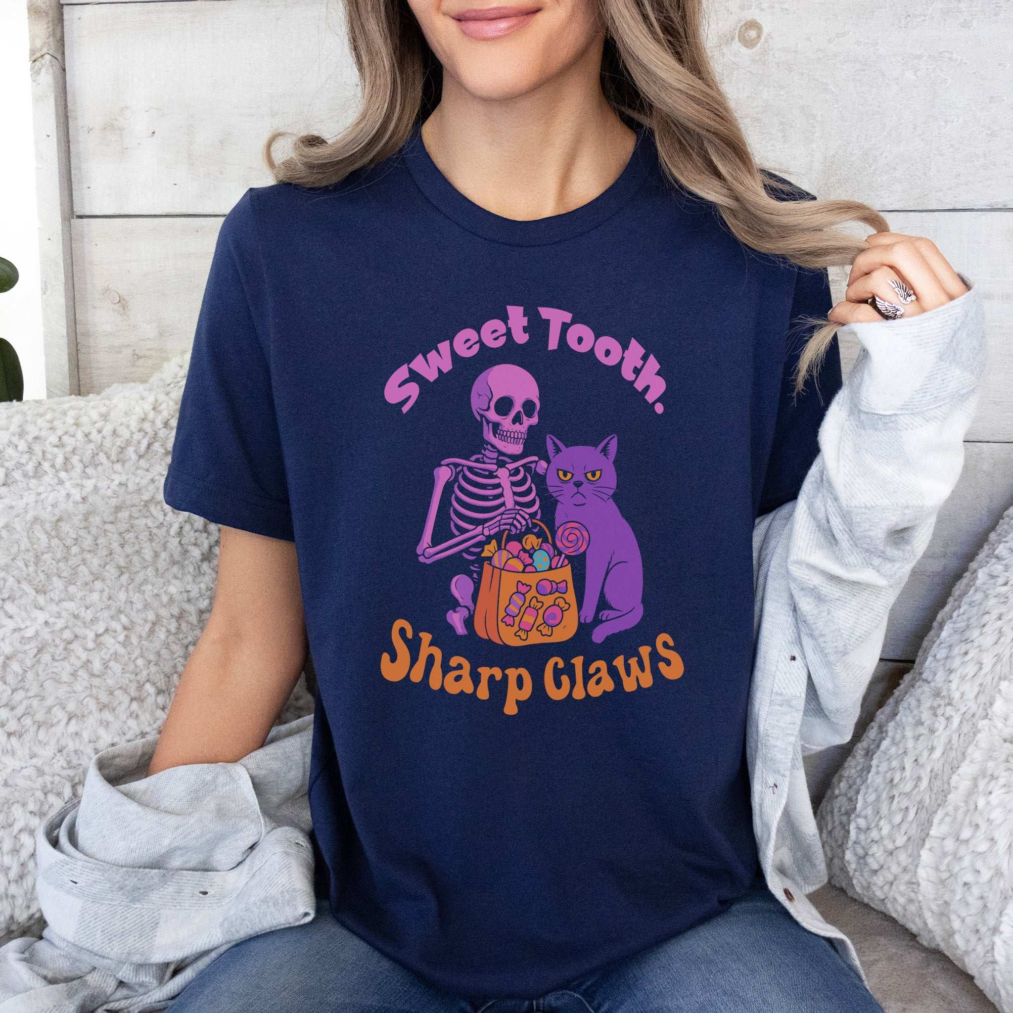 Skeleton and Grumpy Cat Halloween T-shirt with text 'Sweet Tooth, Sharp Claws' on a navy background.