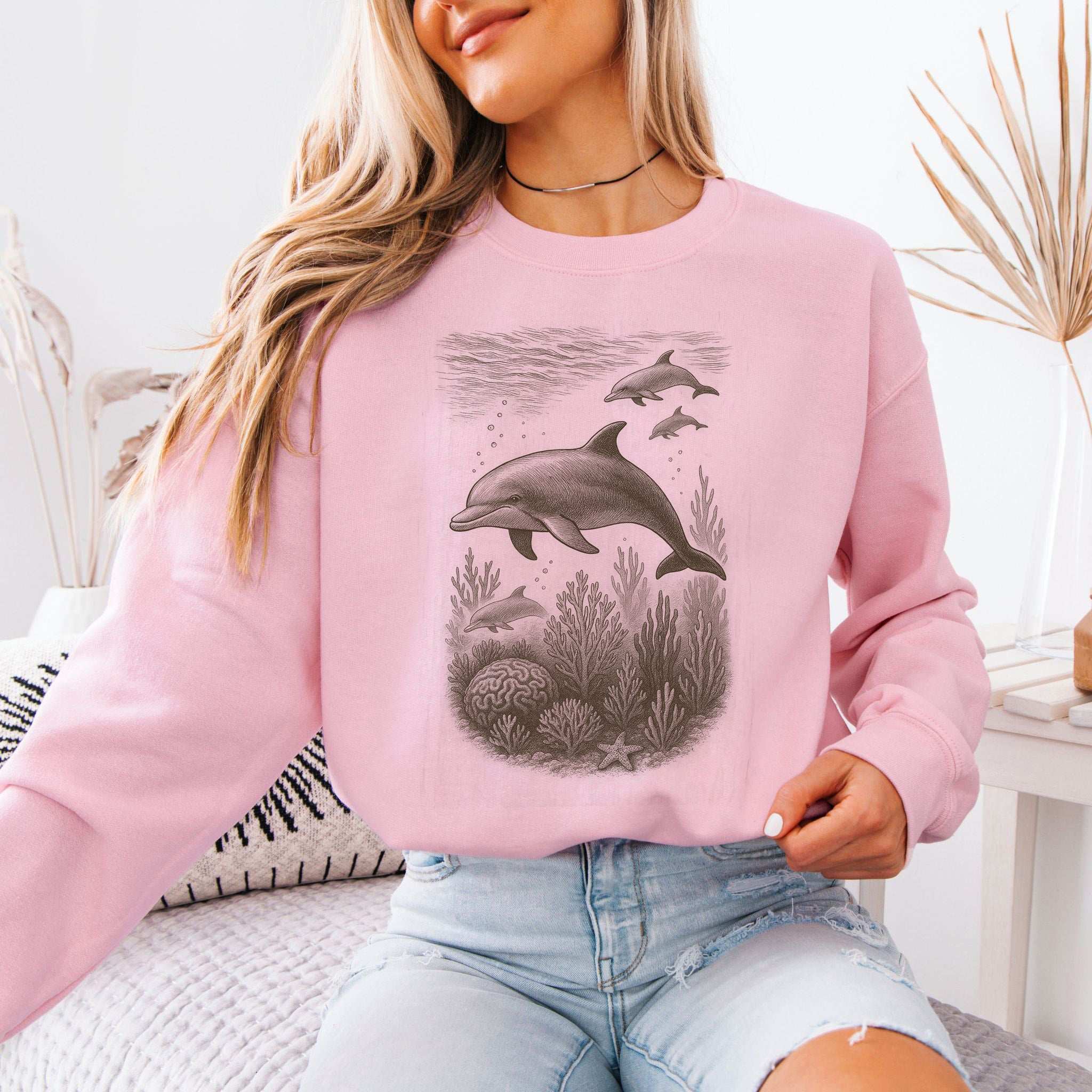 Dolphins and coral reef sketch on a cozy pink sweatshirt, perfect for ocean spirit animal lovers.