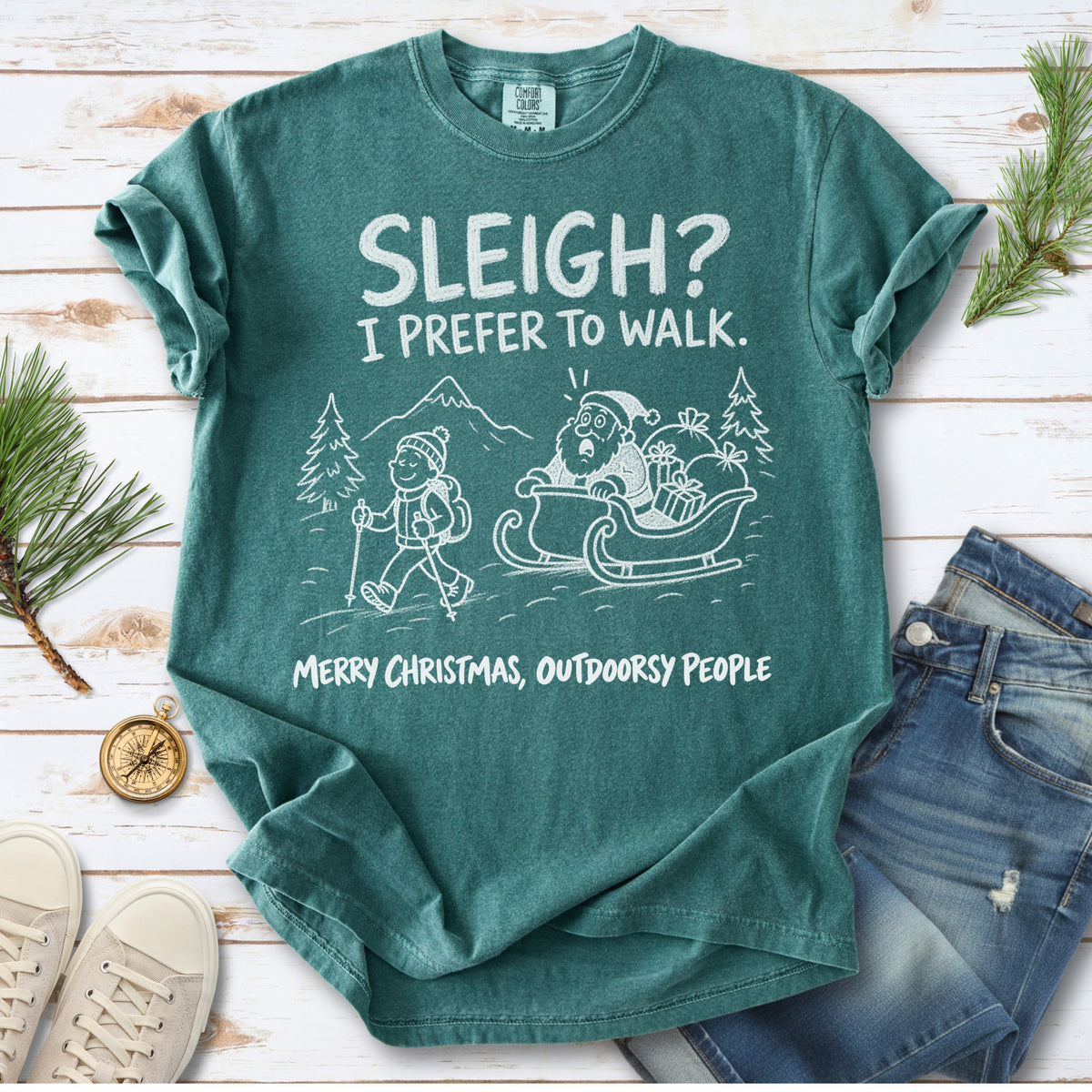 A hiker with trekking poles and a surprised Santa in his sleigh against a mountain backdrop, doodle line-art style design on a Blue Spruce T-shirt
