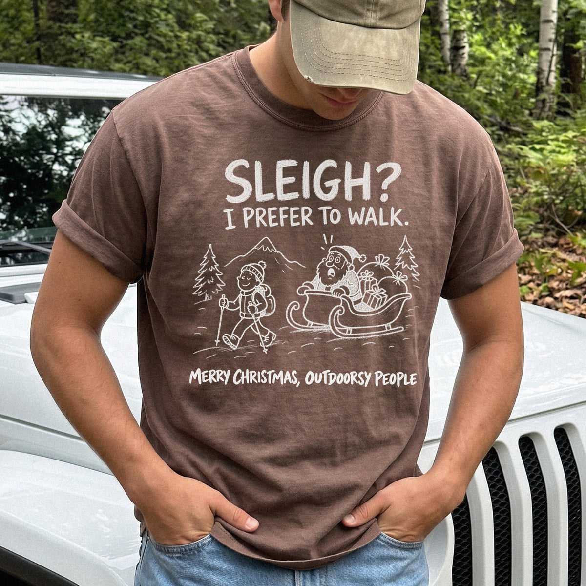 Man wearing an Espresso T-shirt printed with a hiker with trekking poles and a surprised Santa in his sleigh against a mountain backdrop, doodle line-art style