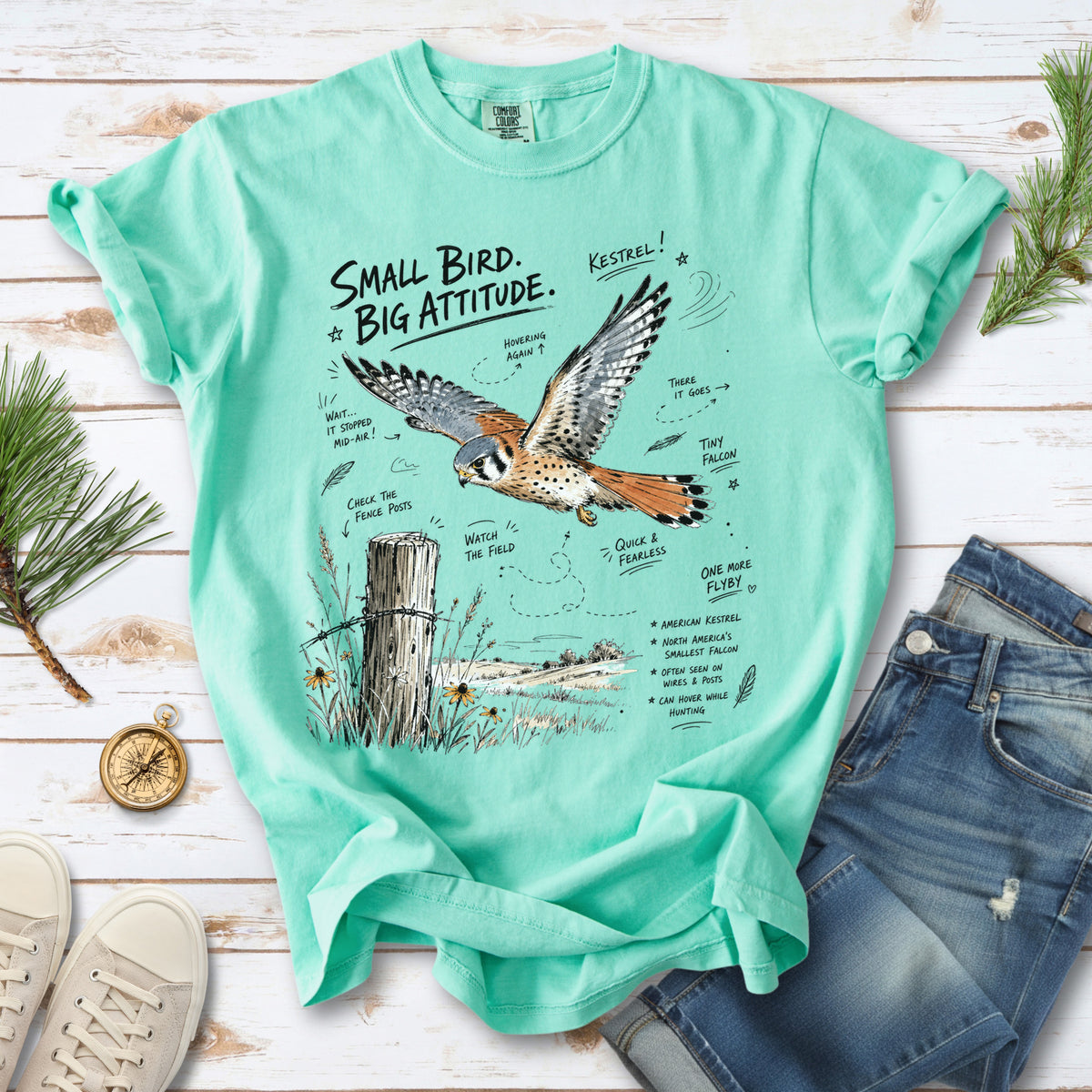 Small Bird, Big Attitude Comfort Colors Shirt – American Kestrel design of an American Kestrel illustrated in mid-flight above an open field, with fence-post details and field-note style callouts, printed on an Island Reef T-shirt.