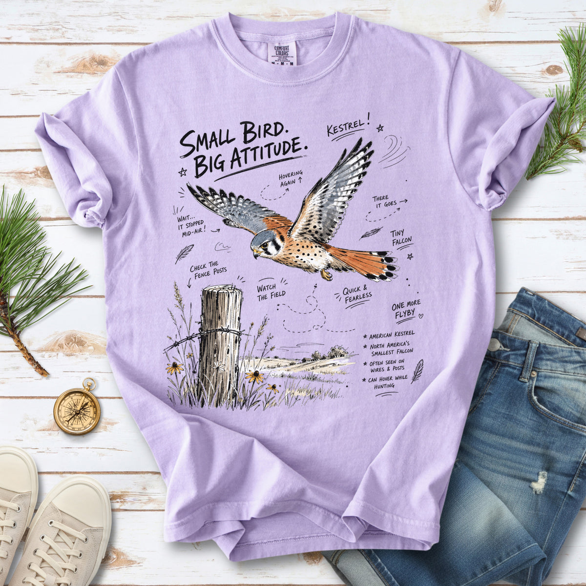 Small Bird, Big Attitude Comfort Colors Shirt – American Kestrel design of an American Kestrel illustrated in mid-flight above an open field, with fence-post details and field-note style callouts, printed on an Orchid T-shirt.