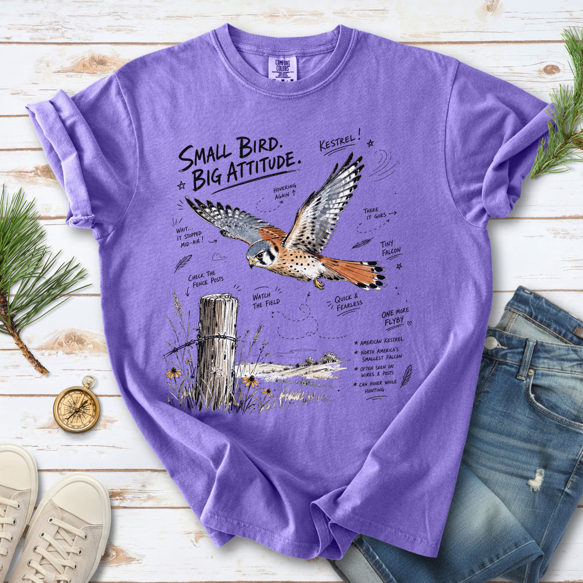 Small Bird, Big Attitude Comfort Colors Shirt – American Kestrel design of an American Kestrel illustrated in mid-flight above an open field, with fence-post details and field-note style callouts, printed on a Violet T-shirt.