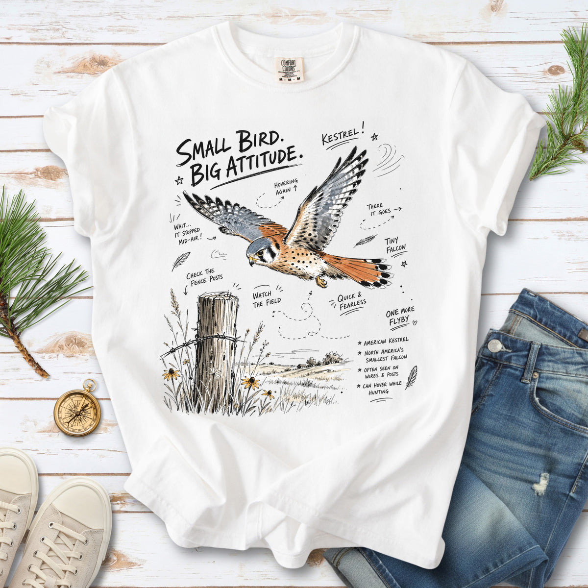 Small Bird, Big Attitude Comfort Colors Shirt – American Kestrel design of an American Kestrel illustrated in mid-flight above an open field, with fence-post details and field-note style callouts, printed on a White T-shirt.