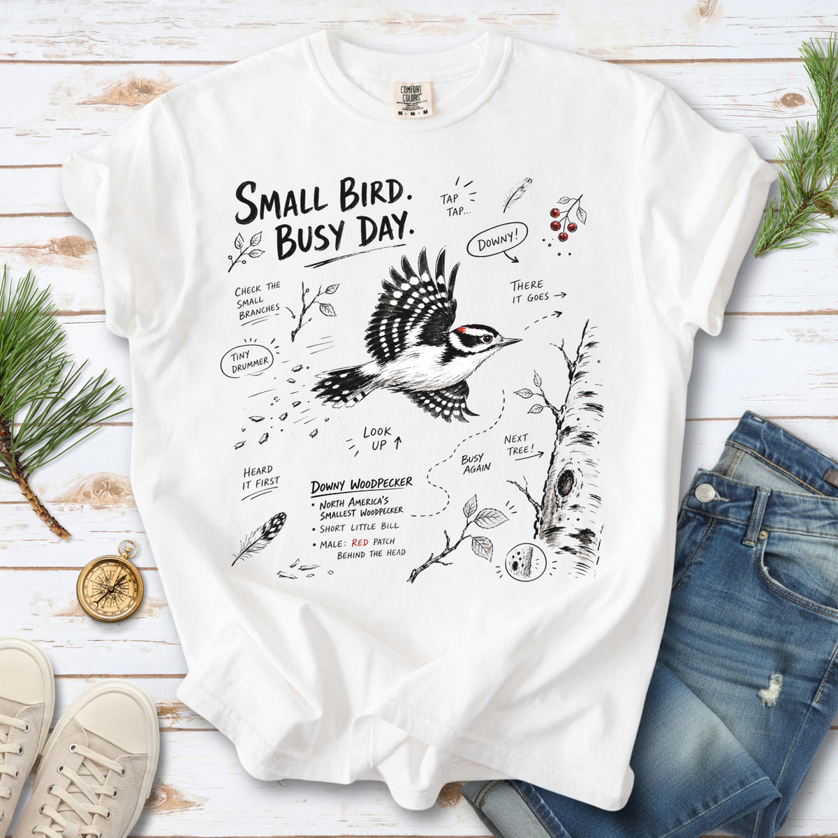 Small Bird Busy Day Comfort Colors Shirt – Downy Woodpecker design of a Downy Woodpecker illustrated in motion, along with sketch-style notes, branches, and tree-trunk details, printed on a White T-shirt.
