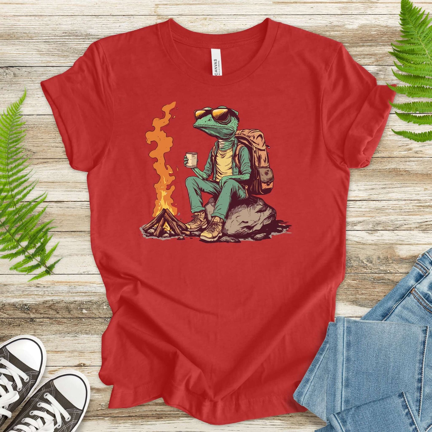 Chameleon sitting near a campfire t-shirt in red, depicting a chameleon in hiking gear enjoying a cozy brew.