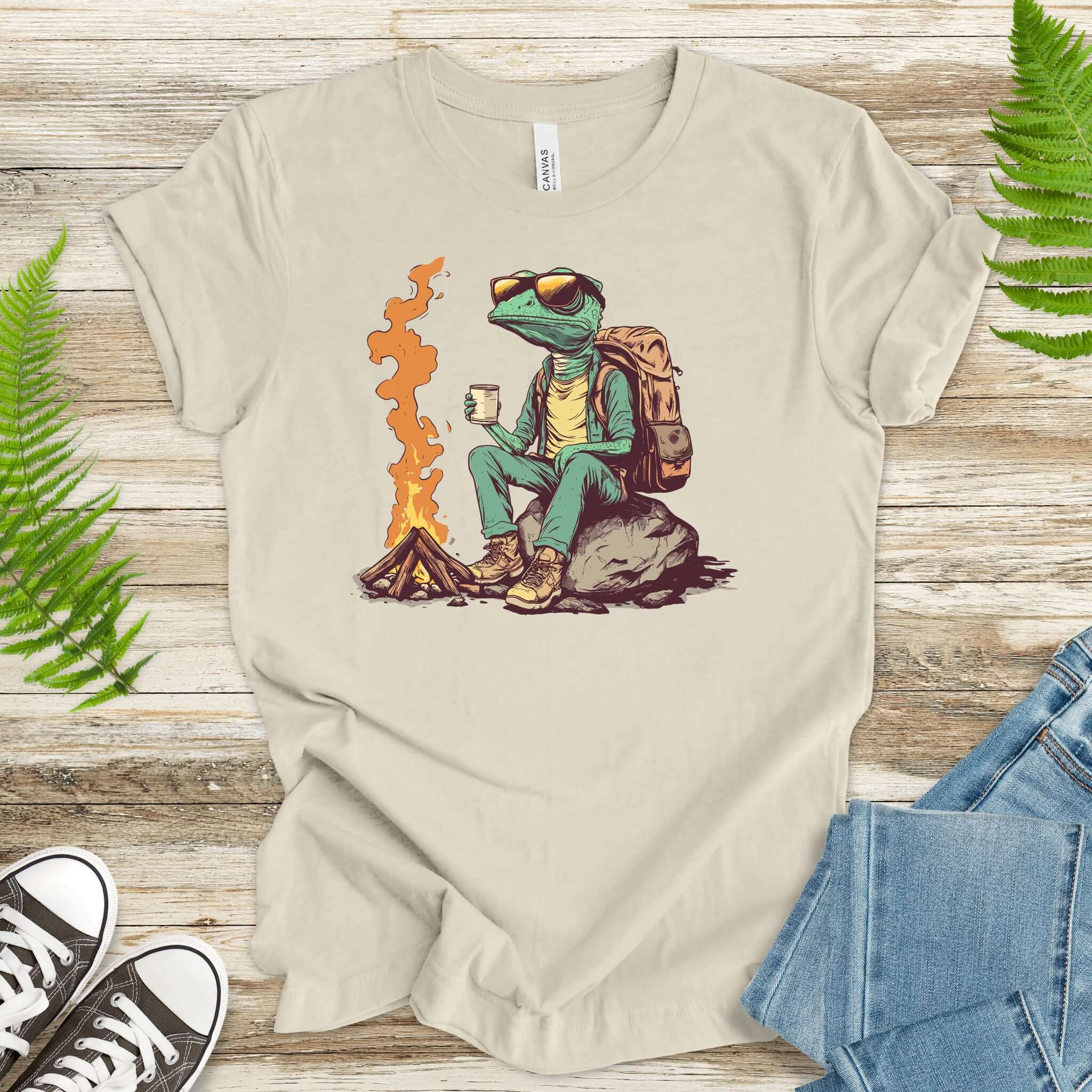 Chameleon T-shirt featuring a chameleon by a campfire, enjoying a drink and perfect for outdoor enthusiasts.