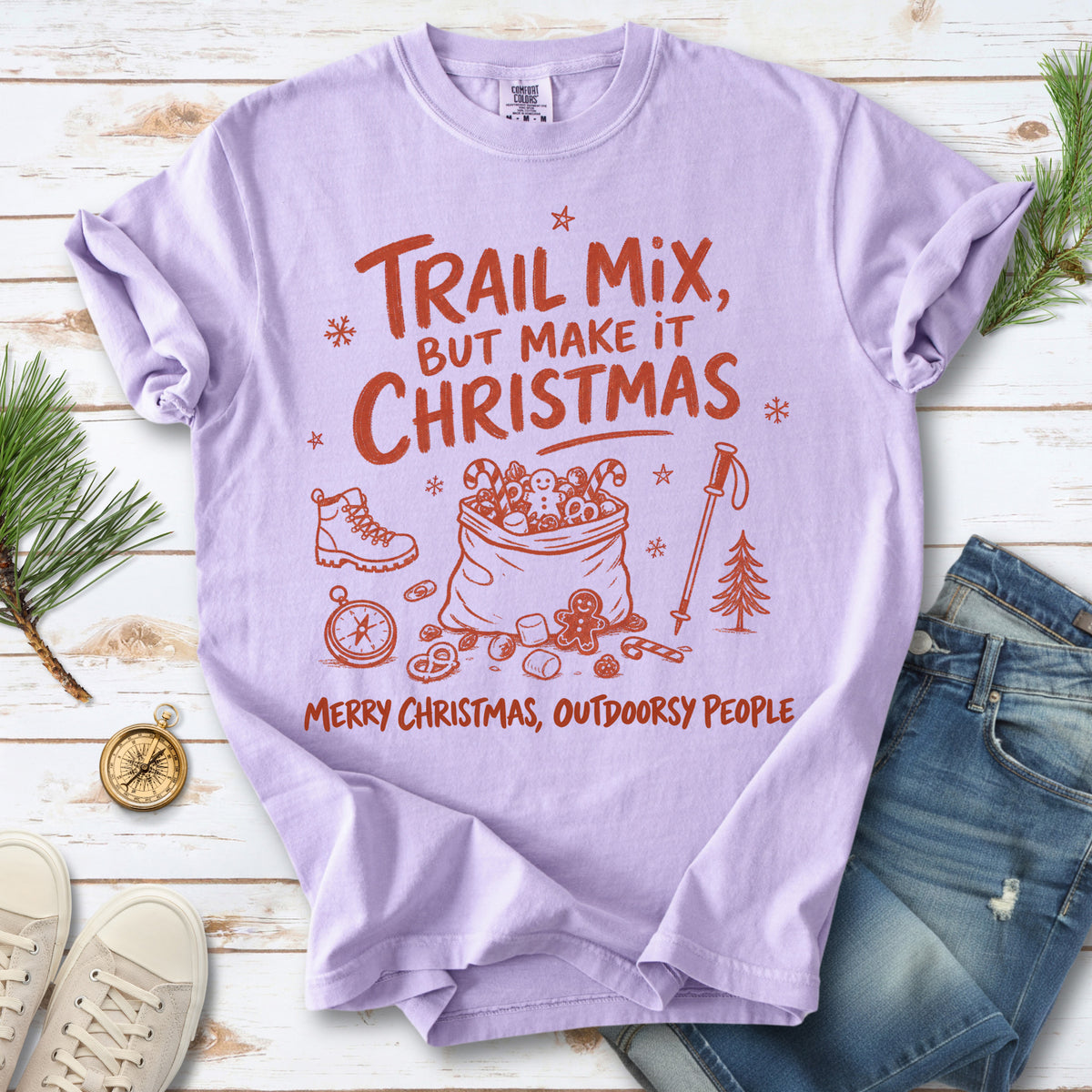 Festive trail snacks, candy canes, a gingerbread cookie, a hiking boot, compass, and trekking pole, doodle style design on an Orchid T-shirt