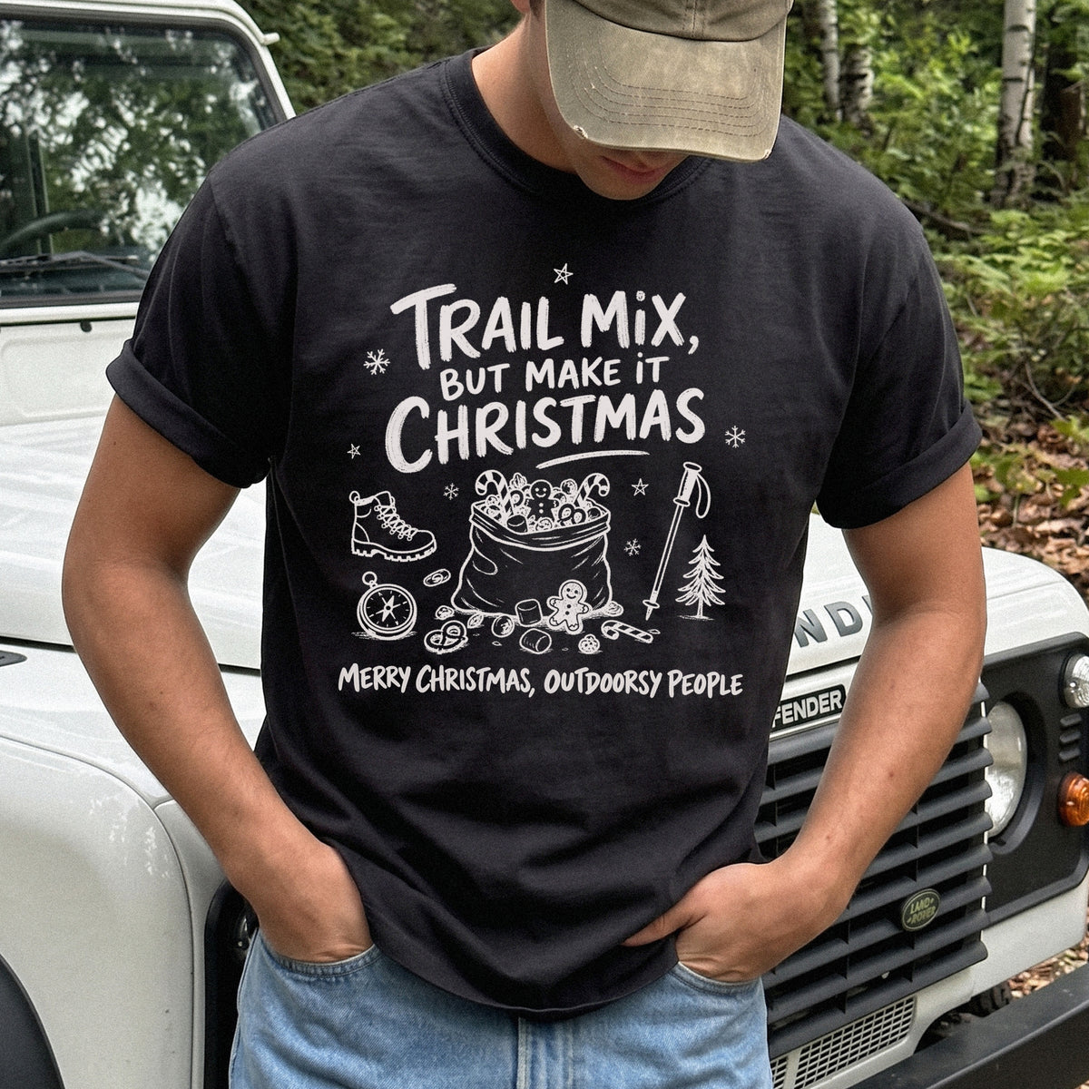 Man wearing a Black T-shirt printed with festive trail snacks, candy canes, a gingerbread cookie, a hiking boot, compass, and trekking pole, doodle style