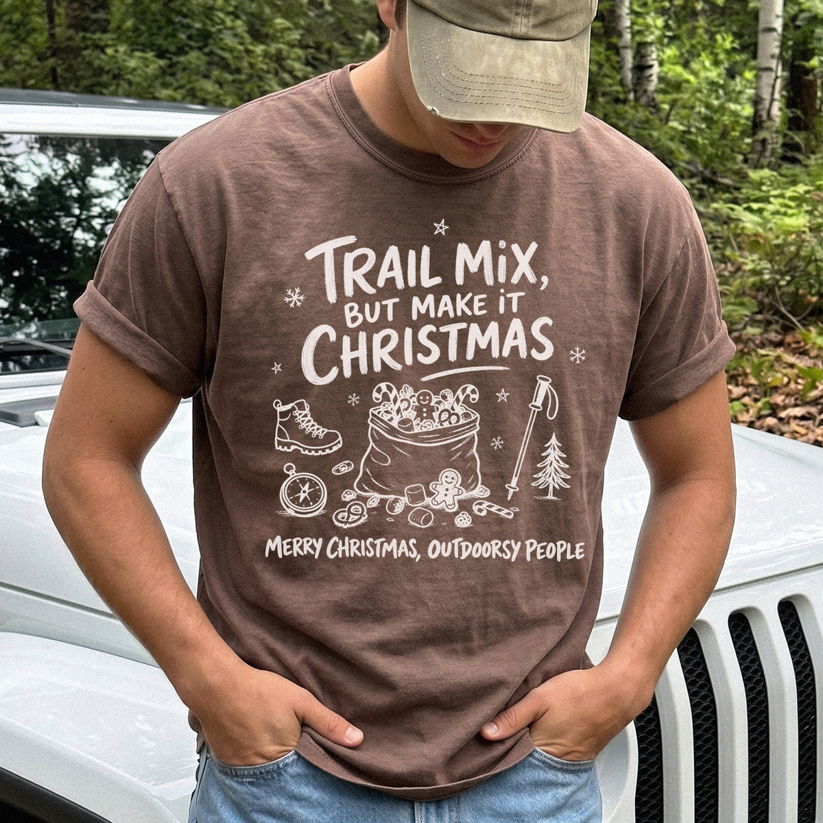 Man wearing an Espresso T-shirt printed with festive trail snacks, candy canes, a gingerbread cookie, a hiking boot, compass, and trekking pole, doodle style