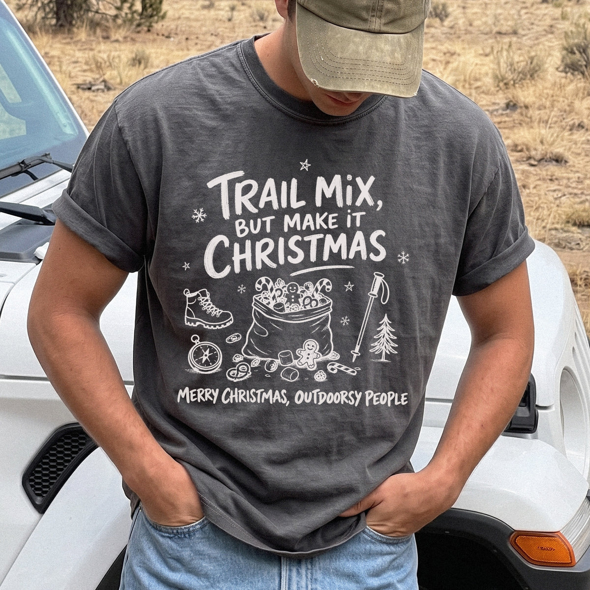 Man wearing a Pepper T-shirt printed with festive trail snacks, candy canes, a gingerbread cookie, a hiking boot, compass, and trekking pole, doodle style