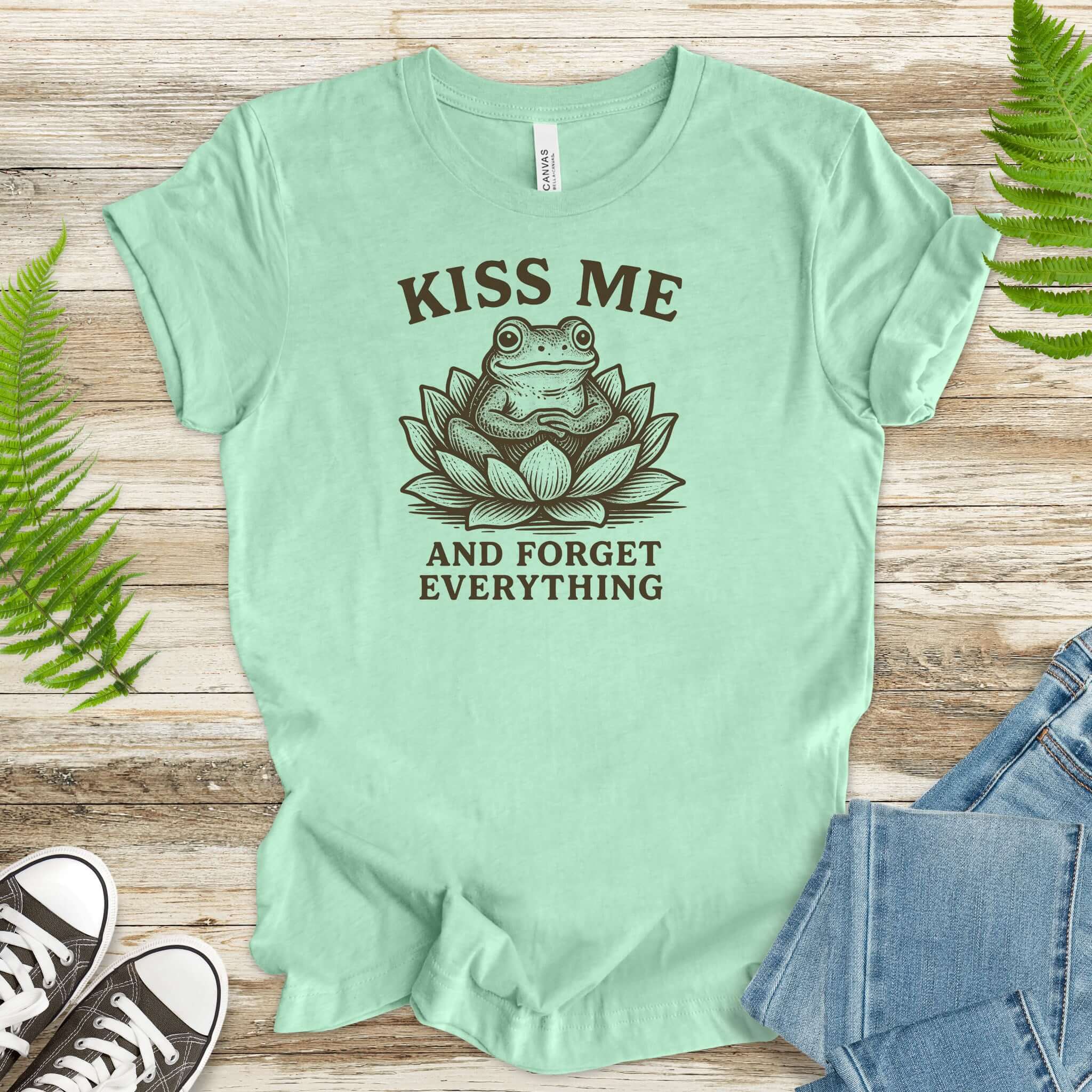 Kiss Me and Forget Everything Tee featuring a funny frog in a lotus flower on a mint green shirt.