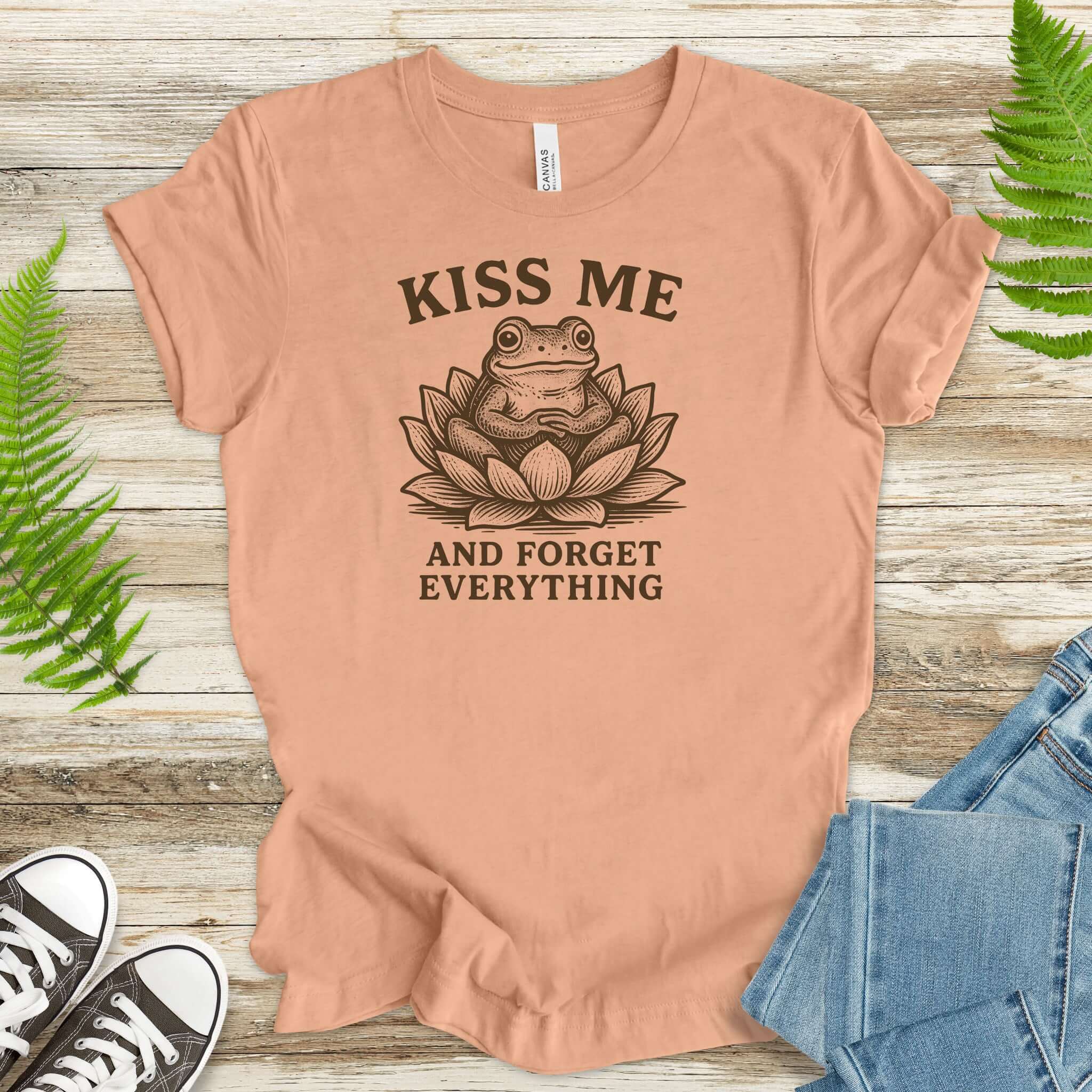 Kiss Me and Forget Everything tee featuring a funny frog in a lotus flower, perfect for whimsical lovers.