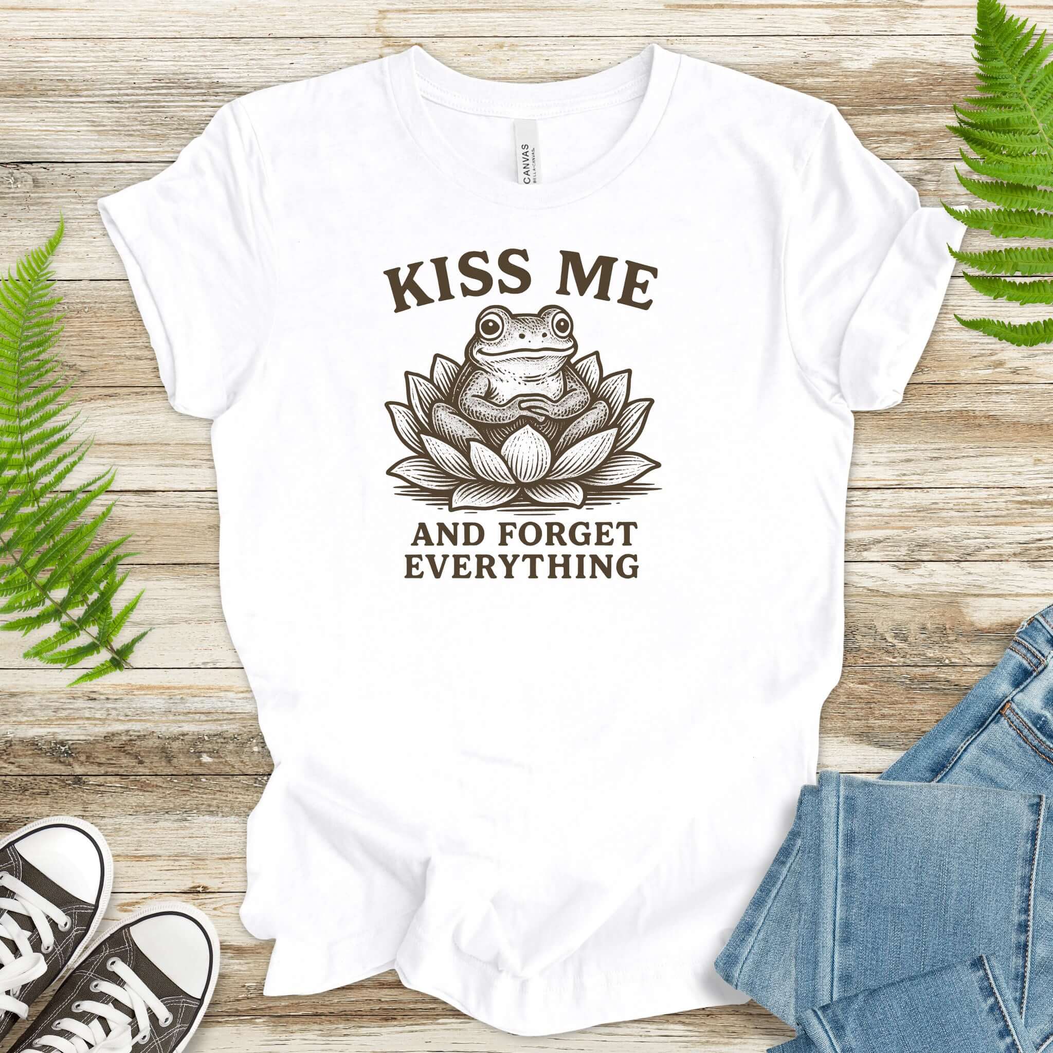 Funny frog t-shirt with 'Kiss Me and Forget Everything' slogan, featuring a whimsical lotus flower design.