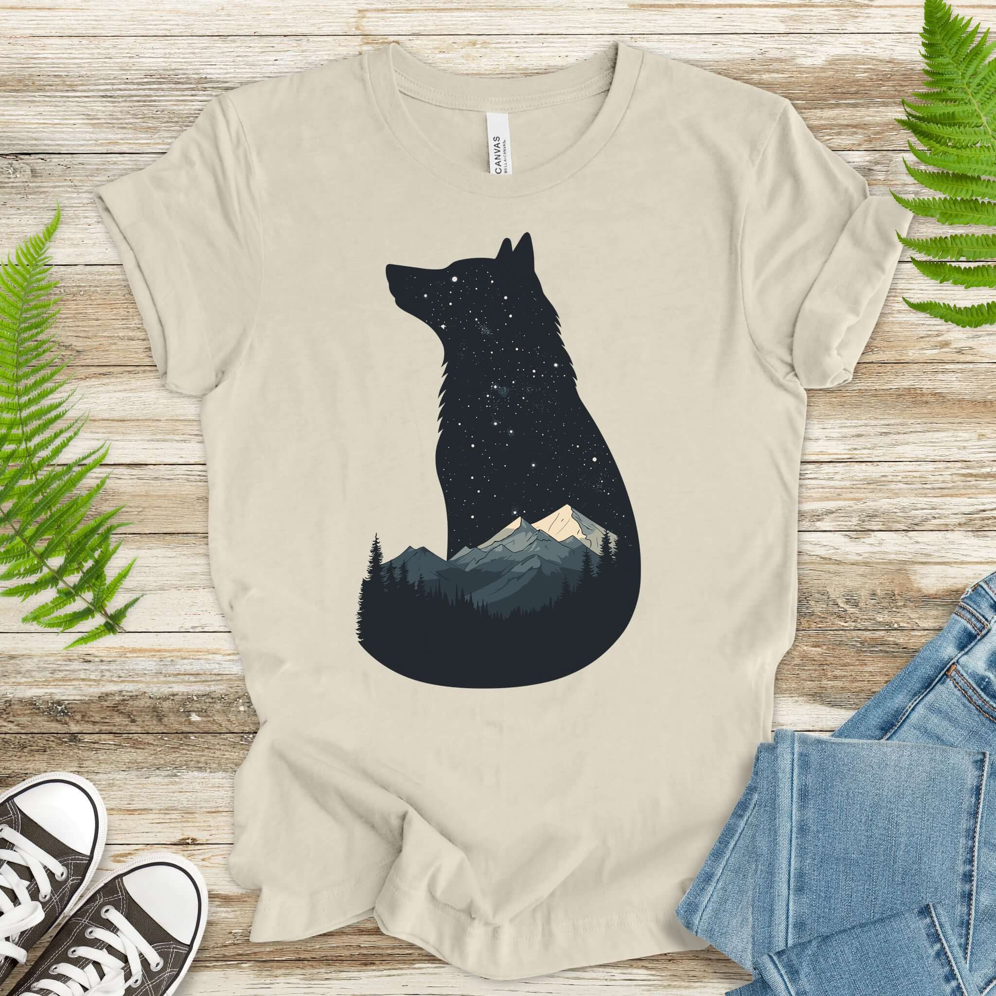 Wolf silhouette t-shirt with night mountain scene, featuring stars and moon against a light background.